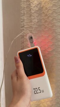 Hand holding a portable power bank charging and powering a string of colorful led fairy lights showing modern mobile technology and festive decorative illumination