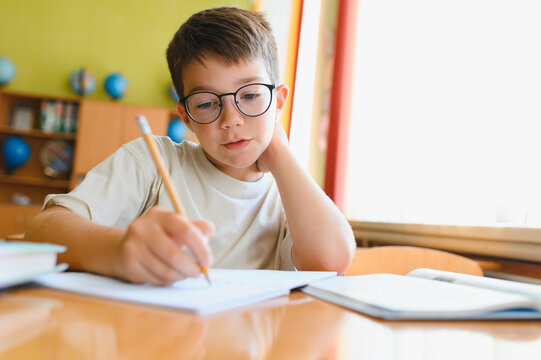 Elementary school student writing in notebook at desk