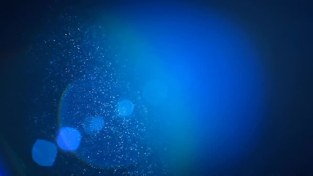 Abstract blue light particles with glowing bokeh effect on dark background for modern digital design