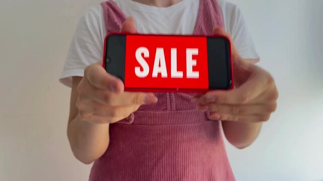Woman holding a mobile phone with a red sale advertisement on the screen, isolated on a white background. Black friday promotion and online shopping concept on a smartphone