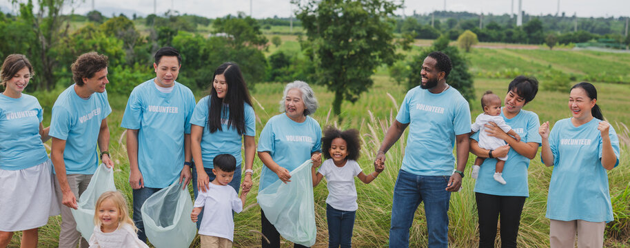 Group smiles while collecting trash in green field