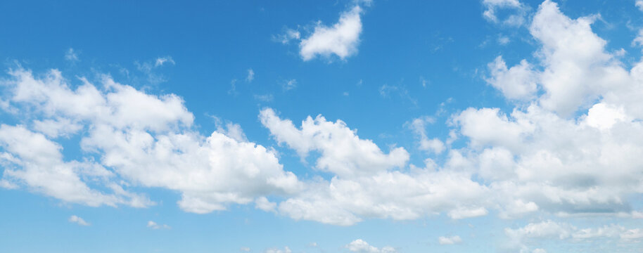 Soft clouds drift across vast, clear blue sky