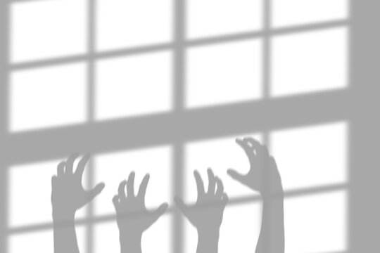 A creepy shadow of human hands reaching up against a bright window pane cast on a wall isolated on a plain and transparent background area