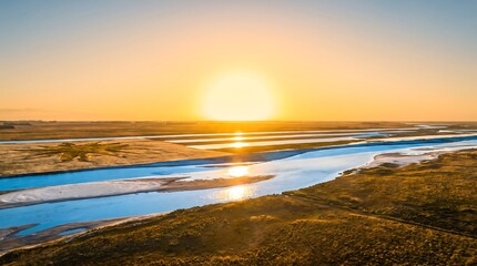 Obraz premium Serene sunrise over a winding river through lush green hills and golden light