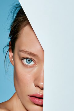 Close-Up Portrait of Woman with Half-Face Hidden Behind White Panel on Blue Background