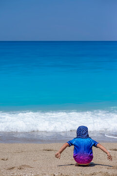 girl palying on the beach wearing sun protective clothes