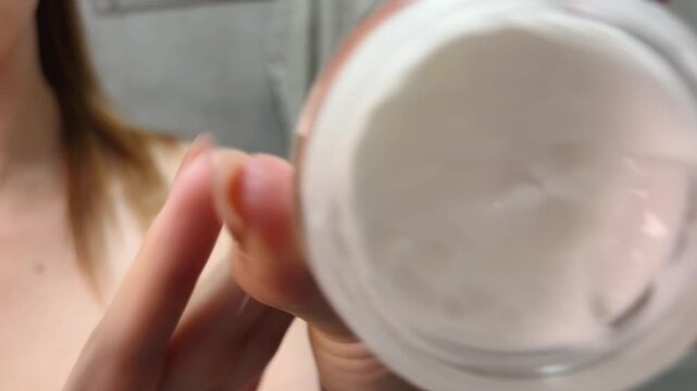Woman applying moisturizing beauty cream, dipping finger in cosmetic jar for skincare routine, close up shot of hands holding natural lotion with smooth texture