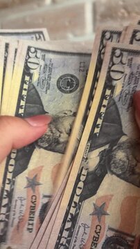 Woman's hands counting fifty dollar bills, us currency close up shot showcasing american cash, finance, and wealth, highlighting financial transactions and economic concepts