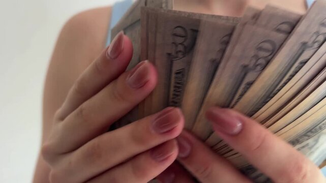 Woman's hands with manicure counting a large amount of fifty dollar bills, representing wealth, income, savings, and the concept of a successful financial transaction