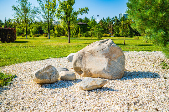 Large smooth boulders and white gravel stones decorative landscaping in summer city park, zen garden design concept