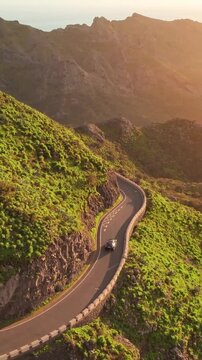 Aerial View Of A Winding Mountain Road During Golden Hour Sunset With Lush Greenery And Rocky Slopes
