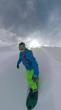 Snowboarder Carving Down A Sunny Snowy Mountain Slope Wearing A Bright Blue Jacket In The Mountains