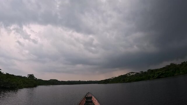 Storm Clouds Over Wide Tropical River in Ecuador Amazon Rainforest, Boat Bow, Dark Sky, Calm Water and Dramatic Wilderness Travel Landscape