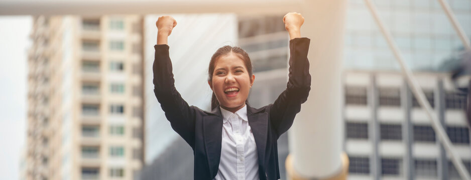 Professional Woman Manager wear black suit feeling success and victory sign hand after complete job with better work business. Asian Happy Business woman raise hand.Successful and victory sign concept