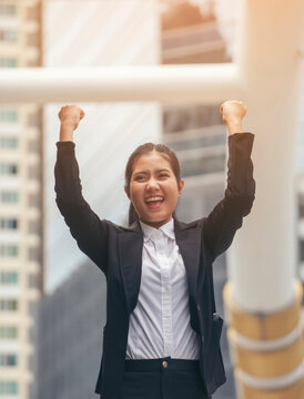 Professional Woman Manager wear black suit feeling success and victory sign hand after complete job with better work business. Asian Happy Business woman raise hand.Successful and victory sign concept