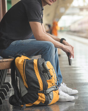 At train station, Asian Backpacker waiting train and planning happy holiday vacation. Young Tourist man searching right direction. Travel concept-vertical image.