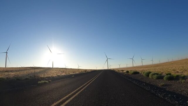 4K action camera driver's point of view of a wind farm near Arlington, Columbia River Gorge, Oregon, USA at morning light. Rotating wind turbines producing clean renewable electricity in strong winds