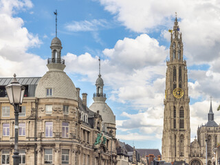 Fototapeta premium Antwerp town in Belgium, Europe. Historic European Cityscape with Grand Architectural Buildings and Soaring Gothic Tower under a Bright Blue Sky with Clouds
