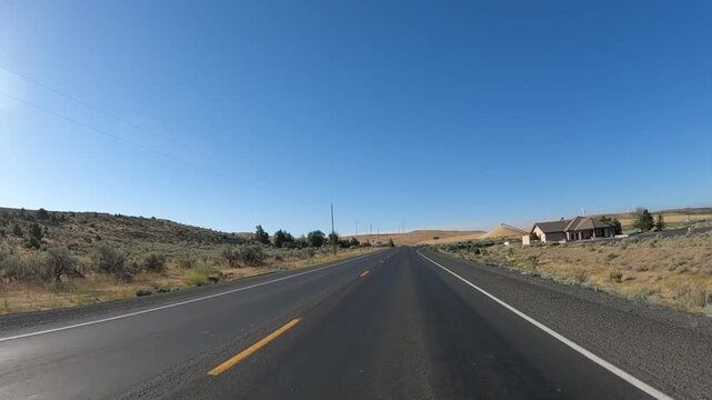 4K action camera footage driving on Highway 19 near Arlington, Oregon, USA, passing a rural grain mill and blending facility with large material piles, open fields and wind turbines