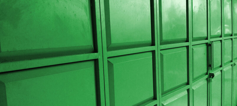A sturdy green folding door or metal security gate featuring a pattern of raised rectangular panels.