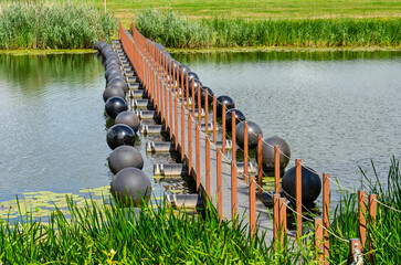 Obraz premium Den Nul, The Netherlands, July 20, 2026: view from the southeast towards the innovative floating pedestrian bridge across the Lange Kolk river channel