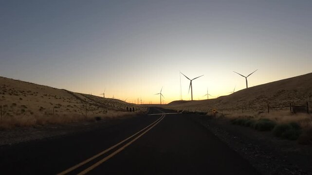 4K action camera driver's point of view of a wind farm near Arlington, Columbia River Gorge, Oregon, USA at morning light. Rotating wind turbines producing clean renewable electricity in strong winds