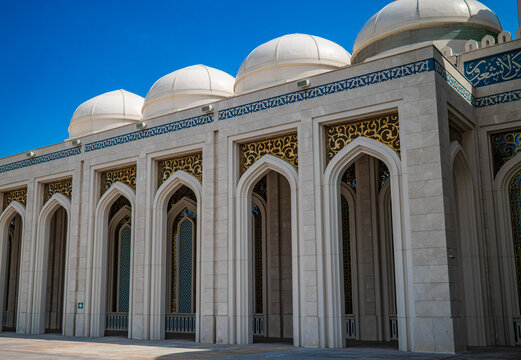 White grand Nursultan mosque with blue domes and arched colonnade against blue sky in Astana Kazakhstan, Islamic architecture concept