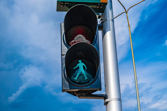 Green pedestrian walk signal traffic light against deep blue sky, urban infrastructure concept