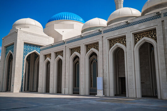 White grand Nursultan mosque with blue domes and arched colonnade against blue sky in Astana Kazakhstan, Islamic architecture concept