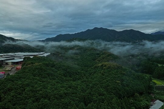 Aerial drone photo of misty mountain valley with industrial facilities in Mihama, Mie, Japan