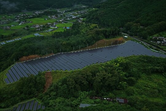 Aerial drone photo of solar panels on hillside with morning mist in Mihama, Mie, Japan