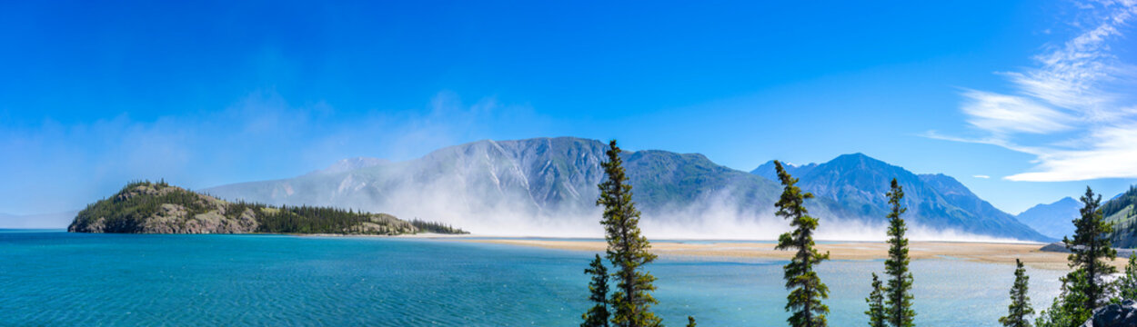 Clouds of dust over Kluane Lake. Dust forms over the former mouth of the Slims River, now dry, as the river has changed direction due to climate change.