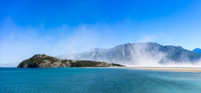 Clouds of dust over Kluane Lake. Dust forms over the former mouth of the Slims River, now dry, as the river has changed direction due to climate change.