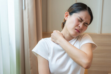 Naklejka premium Asian woman having shoulder and neck pain from working longtime. Shoulder pain is when rotator cuff tendons become inflamed or trapped in your shoulder.