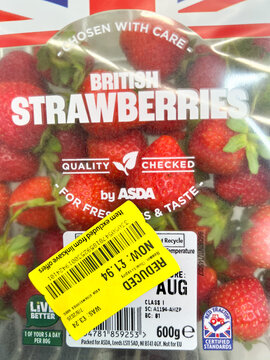 Close up view of a pack of fresh British strawberries from a UK supermarket which are reduced in price with a yellow sticker.