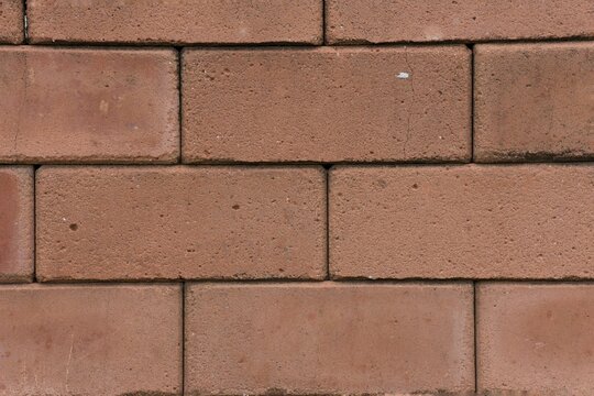Weathered interlocking brick wall background texture with grunge dark mold stains and cracks.
