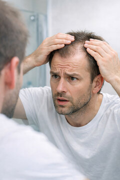 Man looking in the mirror after a close shave, examining his face and the effectiveness of his razor.