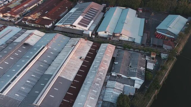 Aerial view of industrial buildings with solar panels. Panels cover roofs of warehouses and factories. Road and parking lots surround the structures. Modern energy solutions for business operations