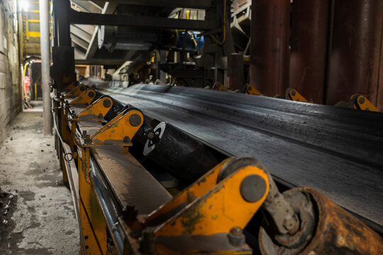 Industrial conveyor belt transporting ore inside a copper mine, showcasing heavy machinery, mining infrastructure and material handling technology in an underground industrial environment.
