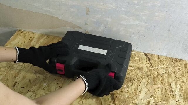 Mechanic opening tool case with cordless screwdriver on workbench, power tools, workshop repair and maintenance concept.