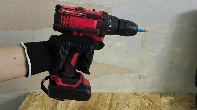 Worker operating cordless screwdriver in workshop, power tool, repair, construction and equipment maintenance concept.