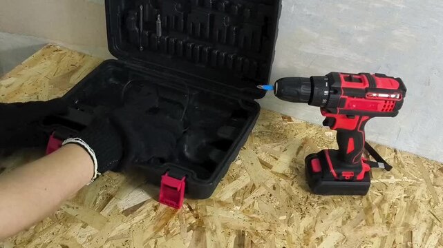 Mechanic putting cordless screwdriver and tools into case after work, workshop organization, repair and maintenance concept.