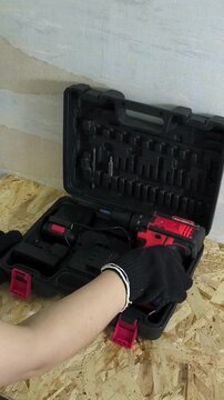 Worker taking cordless screwdriver from tool case in workshop, auto repair, maintenance and power tools concept.