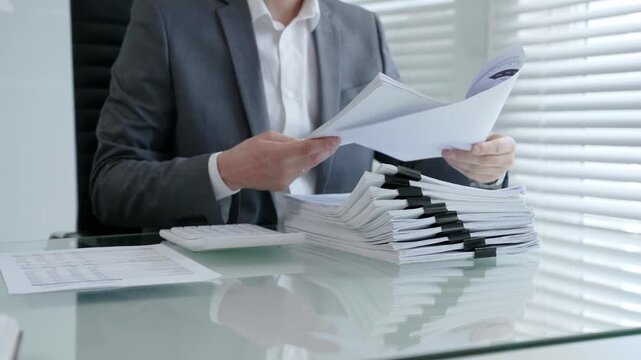 Businessman's hands are busy managing and organizing a large stack of financial papers and business documents