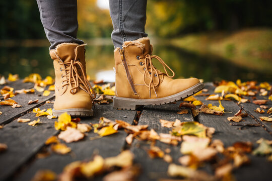 Leather ankle boots. Woman in beige shoe standing in public park. Autumn fashion style