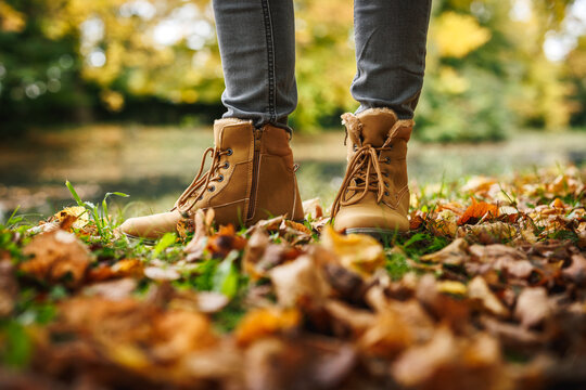 Leather ankle boots. Woman in beige shoe standing in public park. Autumn fashion style