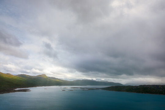 Dramatic landscape view of Tyinholmen lake and distant mountains and clouds, Norway