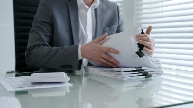 Businessman's hands are busy managing and organizing a large stack of financial papers and business documents