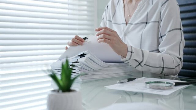 Financial auditor reviewing company documents, checking tax compliance reporting, conducting a detailed investigation, and thoroughly analyzing business paperwork for legal adherence