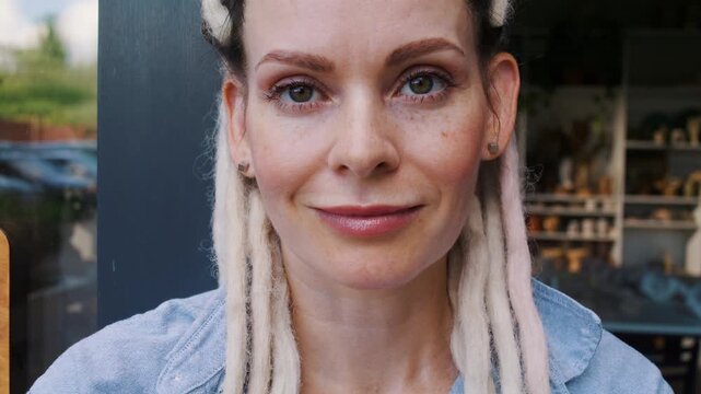 Woman potter smiles standing near entrance of ceramic art studio